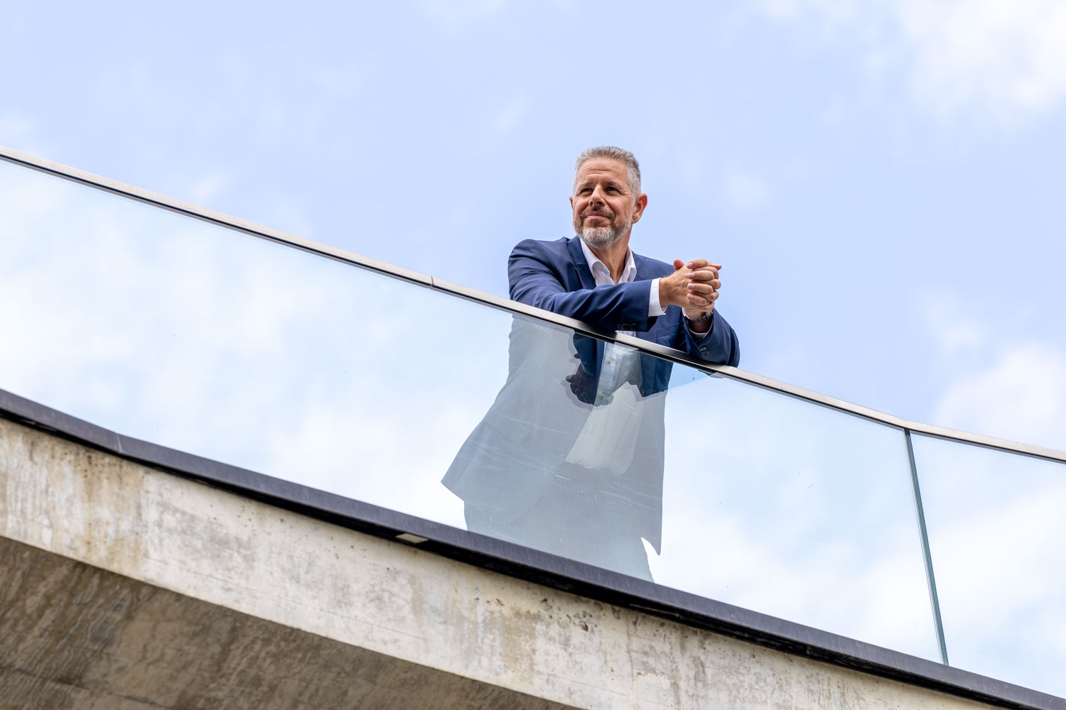 Portrait von Berater und Executive Coach für Führung und Kommunikation Jürgen Pfeiler, der auf einer Brüstung steht und in die Ferne schaut.